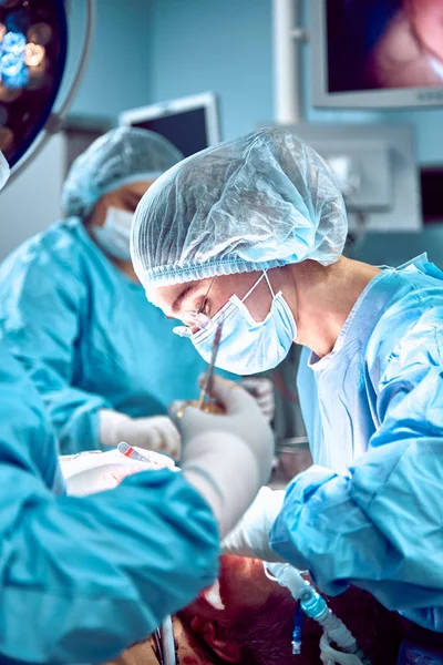 Onların çalışma sırasında hastaya operasyon Masası çevresindeki birkaç cerrahlar — Stok fotoğraf