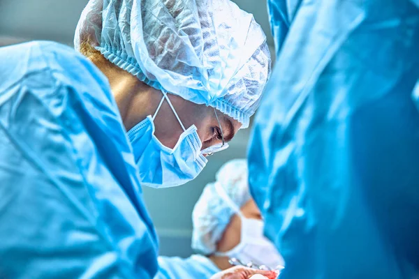 Nahaufnahme Porträt einer jungen Chirurgin mit Schutzmaske und Hut während der Operation. Gesundheitswesen, medizinische Ausbildung, chirurgisches Konzept — Stockfoto