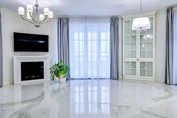 Interior minimalista da sala de estar em tom claro com piso de mármore, grandes janelas e lareira sob TV — Fotografia de Stock