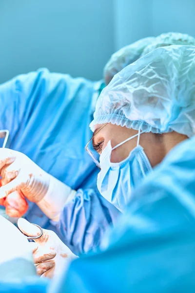 Portrait en gros plan d'une jeune chirurgienne portant un masque protecteur et un chapeau pendant l'opération. Soins de santé, éducation médicale, concept de chirurgie — Photo