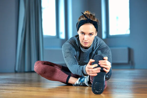 Spor salonunda pencere önünde otururken germe yapmak genç güzel kadın — Stok fotoğraf