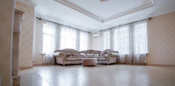 Canto de uma sala de estar muito moderna com um grande sofá cinza em pé por duas janelas — Fotografia de Stock