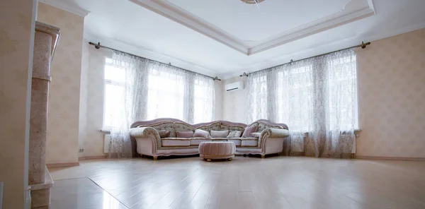 Corner of a very modern living room with a large grey sofa standing by two windows — Stock Photo, Image