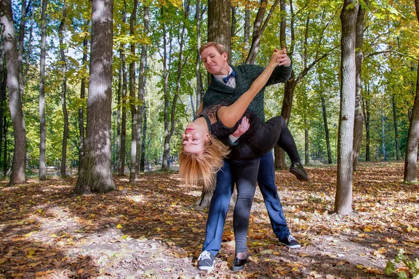 Joven pareja feliz bailando en el parque de otoño. Día soleado, otoño dorado —  Fotos de Stock