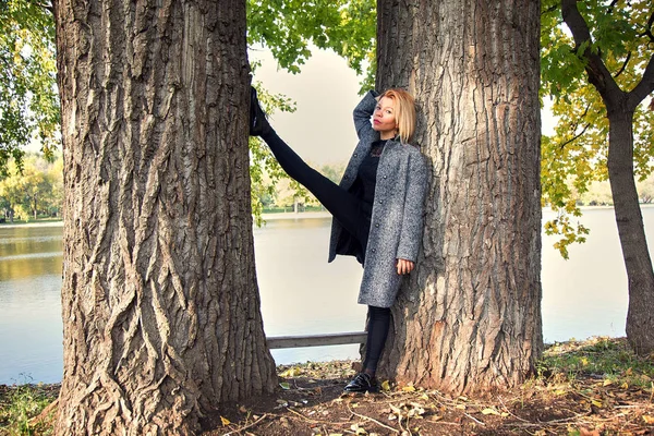 Mooi meisje permanent tussen de bomen met haar benen hoog — Stockfoto