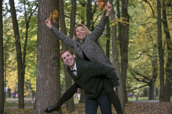 Un cuplu tânăr fericit se joacă cu frunze căzute în parcul de toamnă — Fotografie, imagine de stoc