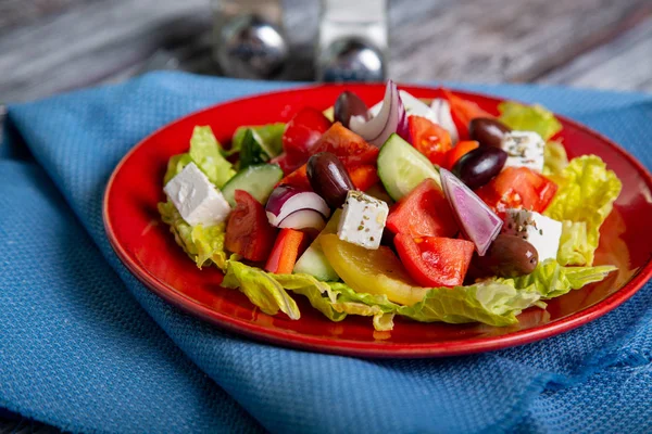 新鮮なキュウリ、トマト、ピーマン、レタス、赤玉ねぎ、フェタチーズと木製の背景にオリーブ オイルとオリーブのギリシャ風サラダ。健康食品 — ストック写真