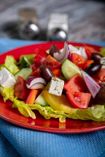新鮮なキュウリ、トマト、ピーマン、レタス、赤玉ねぎ、フェタチーズと木製の背景にオリーブ オイルとオリーブのギリシャ風サラダ。健康食品 — ストック写真