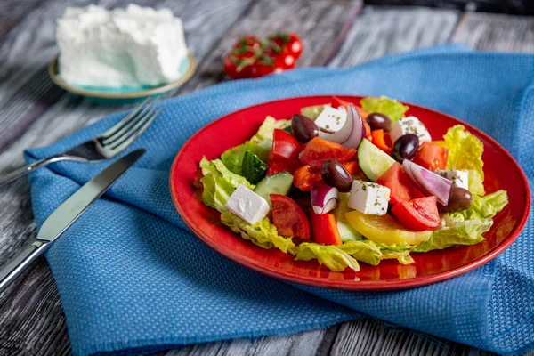 Salada grega de pepino fresco, tomate, pimentão doce, alface, cebola vermelha, queijo feta e azeitonas com azeite sobre fundo de madeira. Alimentos saudáveis — Fotografia de Stock