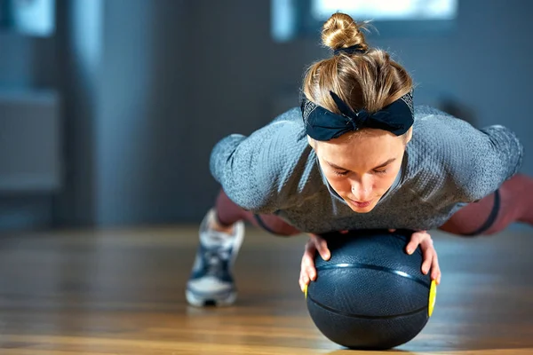 Bela mulher em sportswear posando enquanto sentado no chão com basquete na frente da janela no ginásio Estilo de vida menina saudável e conceito de esporte — Fotografia de Stock