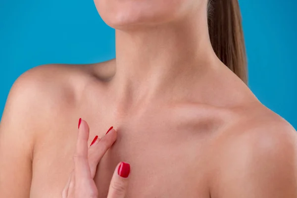 Oříznuté frontview modelu něžně dotýká její obličej a krk. Ženské ruce s přesného hřebíky na modré studio pozadí. Hladké zdravé pleti — Stock fotografie