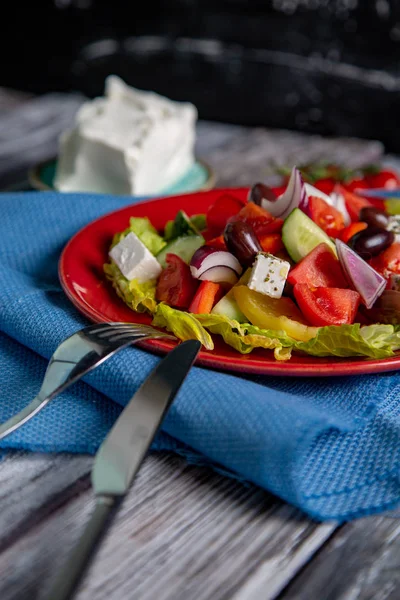 Salada grega de pepino fresco, tomate, pimentão doce, alface, cebola vermelha, queijo feta e azeitonas com azeite sobre fundo de madeira. Alimentos saudáveis — Fotografia de Stock