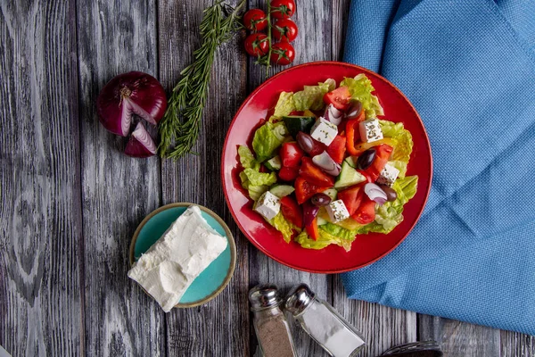 Salada grega de pepino fresco, tomate, pimentão doce, alface, cebola vermelha, queijo feta e azeitonas com azeite sobre fundo de madeira. Alimentos saudáveis — Fotografia de Stock