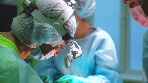 Chirurgen het dragen van beschermende kleding uitvoeren met behulp van de chirurgie gesteriliseerd apparatuur. Medisch Team uitvoeren van chirurgische ingreep in heldere moderne operatiekamer — Stockvideo