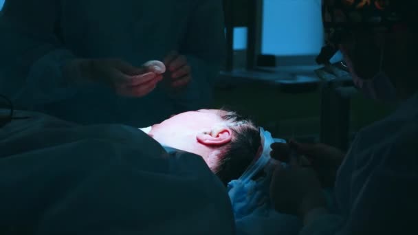 Gesichtsstraffung. Nahaufnahme im Operationssaal des Operationstisches mit dem Patienten. Operation im Gange. — Stockvideo
