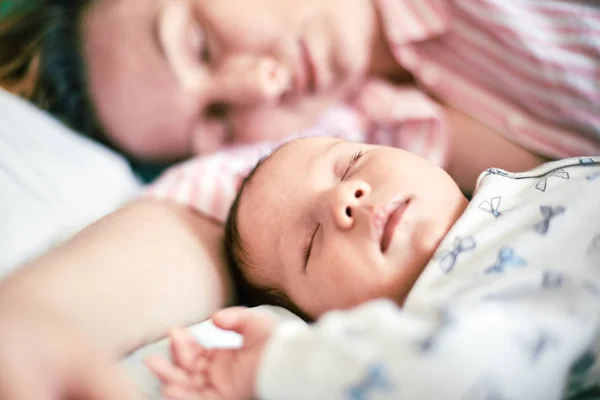 Porträt von Neugeborenem und Mutter, die zusammen auf dem Bett schlafen und ausruhen — Stockfoto