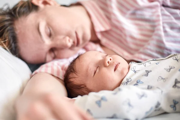 Porträt von Neugeborenem und Mutter, die zusammen auf dem Bett schlafen und ausruhen — Stockfoto