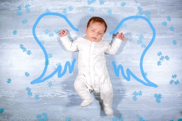 Niedlichen kleinen schlafenden Baby fliegen mit Engelsflügeln über hölzernen Hintergrund. Neugeborenes Baby mit bemalten Engelsflügeln — Stockfoto