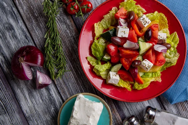 Salada grega de pepino fresco, tomate, pimentão doce, alface, cebola vermelha, queijo feta e azeitonas com azeite sobre fundo de madeira. Alimentos saudáveis — Fotografia de Stock