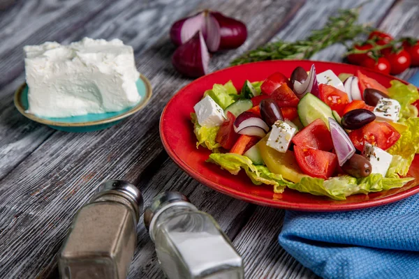 Salada grega de pepino fresco, tomate, pimentão doce, alface, cebola vermelha, queijo feta e azeitonas com azeite sobre fundo de madeira. Alimentos saudáveis — Fotografia de Stock