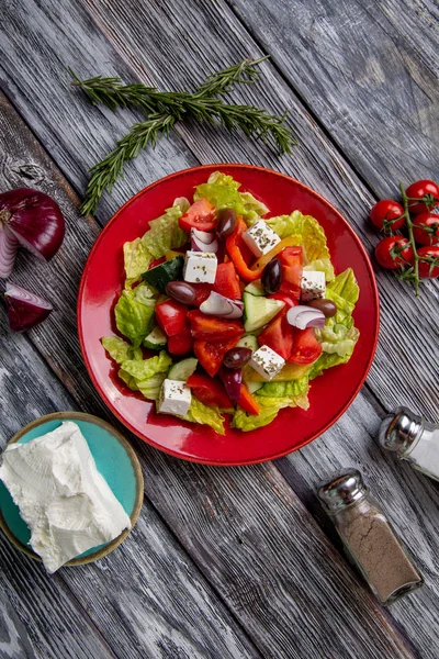 Salada grega de pepino fresco, tomate, pimentão doce, alface, cebola vermelha, queijo feta e azeitonas com azeite sobre fundo de madeira. Alimentos saudáveis — Fotografia de Stock