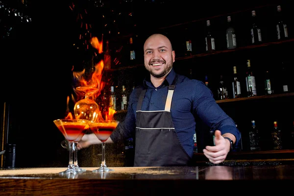Fiery show at the bar. The bartender makes hot alcoholic cocktail and ignites bar. Bartender prepares a fiery cocktail. Fire on bar.