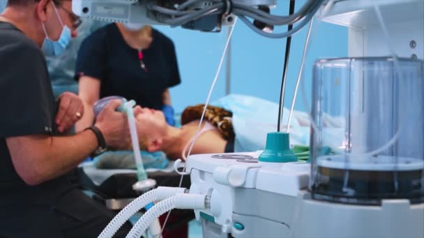 Im Operationssaal, bei der Vorbereitung des Patienten auf die Operation, führt der Anästhesist den Patienten in die Narkose ein. Blick hinter den Ventilator — Stockvideo