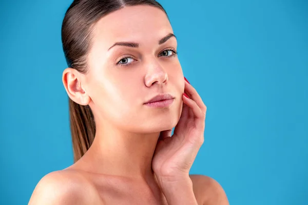 Close up Beauty portrait of young woman brunette smiling and touching her face on blue background. Perfect Fresh Skin. Youth and Skin Care Concept. — Stock Photo, Image