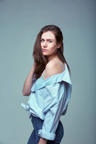 Hermosa chica con ojos azules posando sobre fondo gris — Foto de Stock