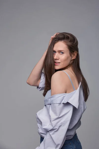 Portrait of a smiling young woman posing over grey background — Stock Photo, Image