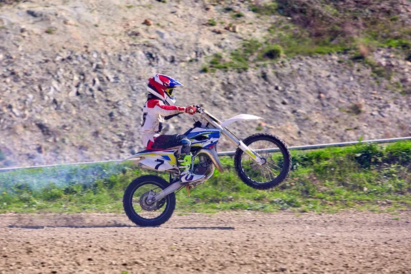 Motociclista su acrobazie moto durante la guida sulla ruota posteriore vista laterale — Foto Stock