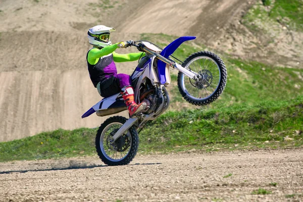 Motociclista su acrobazie moto durante la guida sulla ruota posteriore vista laterale — Foto Stock