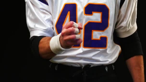 American football player clenching his fist before a big event, giving the impression of tension, concentration or build-up. close up and straight on a black background. — Stock Video
