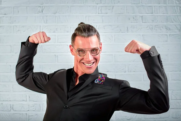 Close up portrait of a happy young businessman wearing glasses dressed in a black suit shows hands cool — Stock Photo, Image