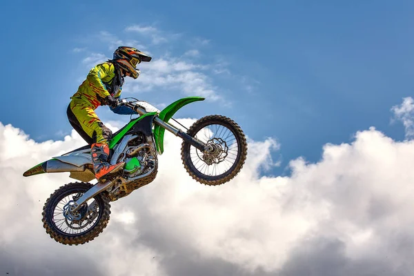 Fundo de esportes extremos - silhueta de motociclista pulando em moto no pôr do sol, contra o céu azul com nuvens — Fotografia de Stock