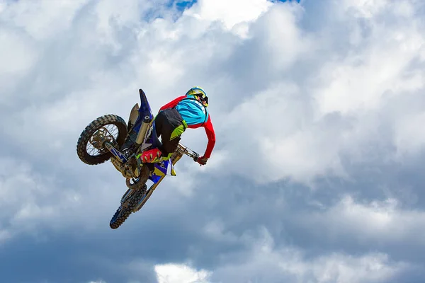На спортивном фоне - силуэт байкера, прыгающего на мотоцикле на закате, на фоне голубого неба с облаками — стоковое фото