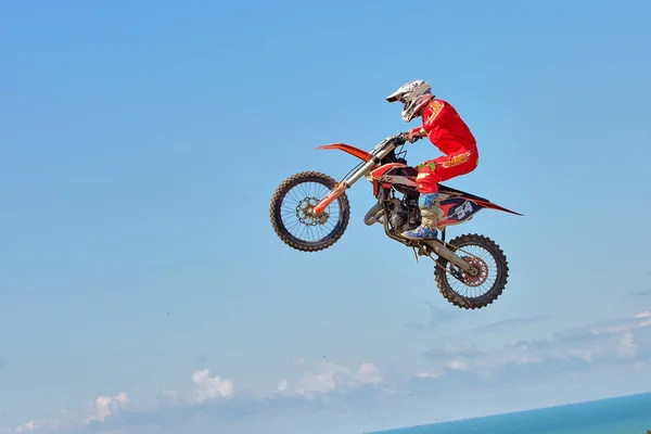 Extremsporthintergrund - Silhouette eines Motorradsprungs bei Sonnenuntergang, vor blauem Himmel mit Wolken — Stockfoto