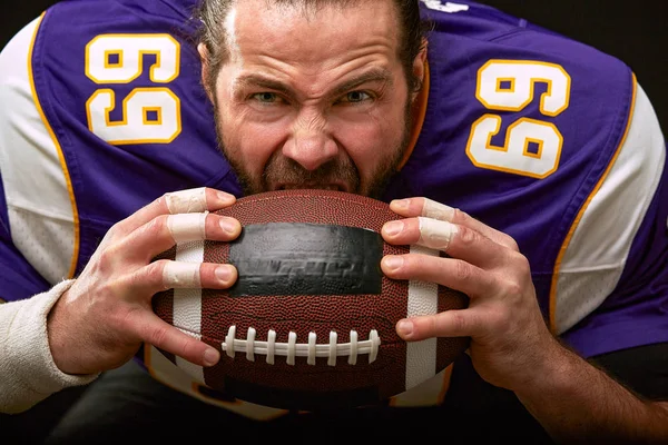 American football player emotional face biting a ball close up