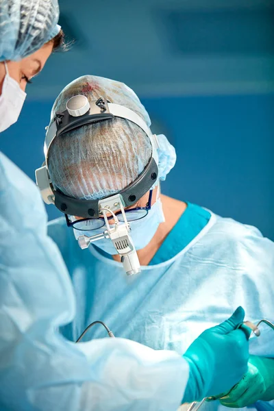 Retrato de un cirujano de cerca. Los cirujanos operan a un paciente. Caras tensas y serias. Operación real. Atmósfera tensada en quirófano . — Foto de Stock