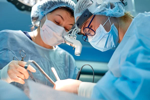 Retrato de cirujanos profesionales durante la cirugía sobre fondo azul. Cirugía conceptual, medicina. Los cirujanos están trabajando en una operación compleja — Foto de Stock