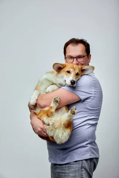 The dog lies on the shoulder of its owner.Welsh Corgi in his owners hands on white background. The concept of people and animals. Copy space — Stock Photo, Image