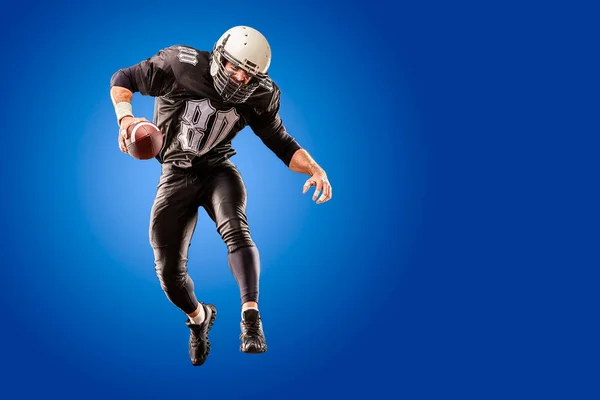 American football player in a jump with a ball on a blue background