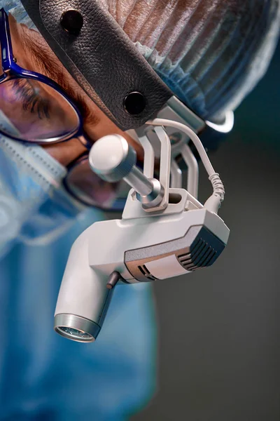 Retrato de perto de uma médica cirurgiã usando máscara protetora e chapéu durante a operação. Saúde, educação médica, conceito de cirurgia . — Fotografia de Stock