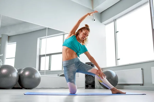 Çekici sporcumuz limbering-up ve onun bacakları ve kolları germe modern damakları stüdyo güzel sportif kız yerde yapıyor — Stok fotoğraf