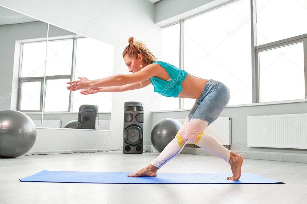 attractive sportswoman doing exercises on the floor in the modern palates studio Beautiful sportive girl limbering-up and stretching her legs and arms