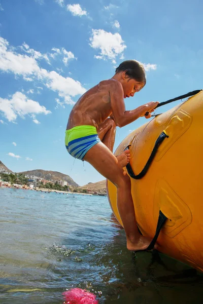 Pojke som spelar på vatten studsmatta på havet på solig dag — Stockfoto