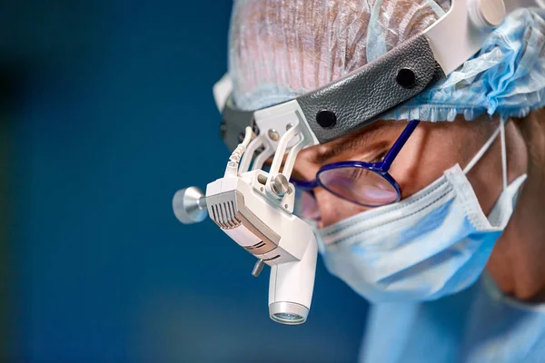 Retrato de perto de uma médica cirurgiã usando máscara protetora e chapéu durante a operação. Saúde, educação médica, conceito de cirurgia . — Fotografia de Stock