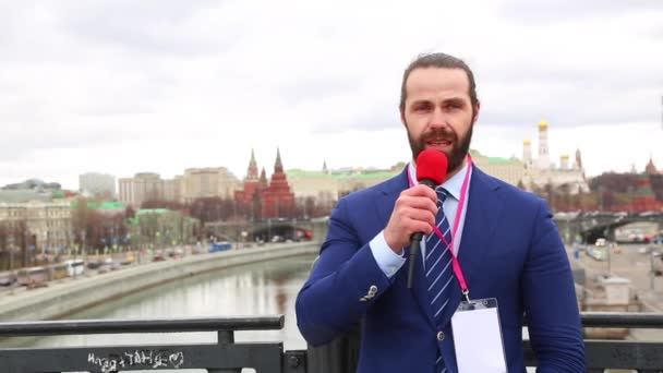 マイクを使って男性記者は、都市の背景にニュース カメラを指示します。ロシア、モスクワ — ストック動画