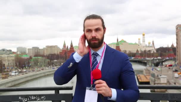 Hombre reportero con un micrófono dice cámara de noticias en el fondo de la ciudad. Rusia, Moscú — Vídeo de stock
