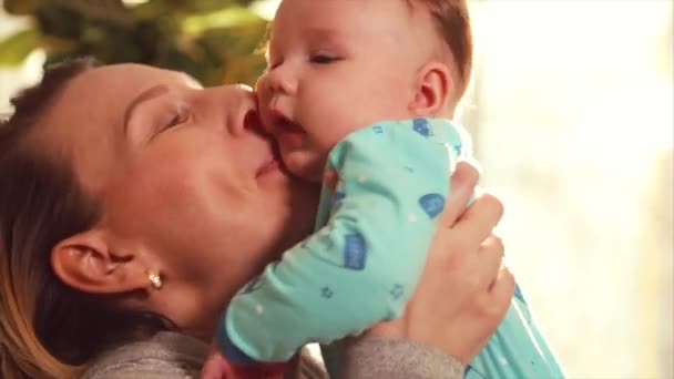 Matka si hraje s dítětem v ruce a objetí proti okno v den ny su — Stock video